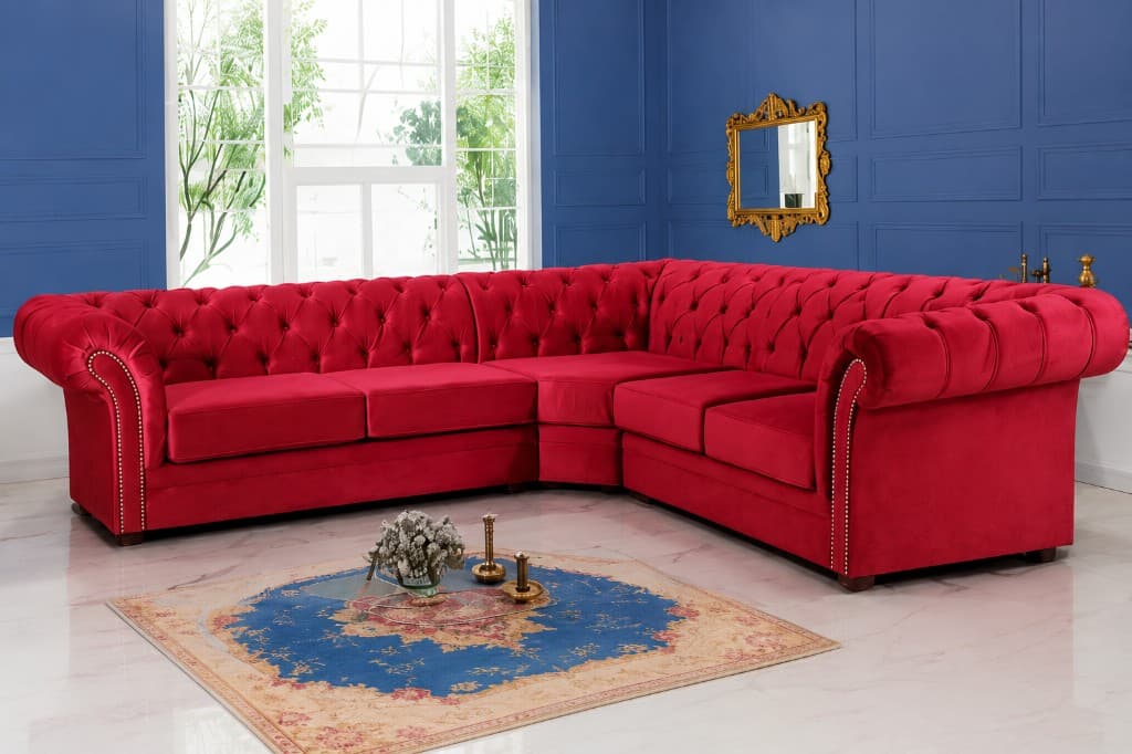 Deep red velvet chesterfield corner sofa in a navy panelled living room